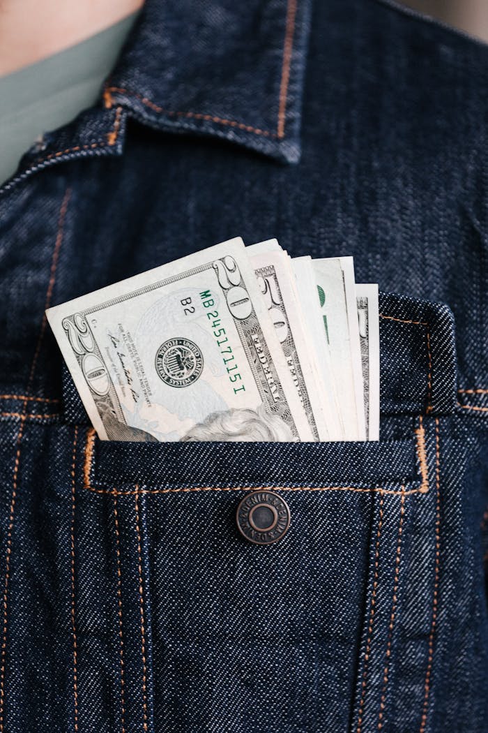 services-03 Close-up of US dollar bills in a denim jacket pocket, symbolizing wealth and finance.