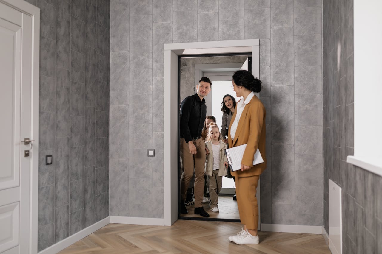 hero-img-01 A family explores a new home with a real estate agent in a modern interior setting.