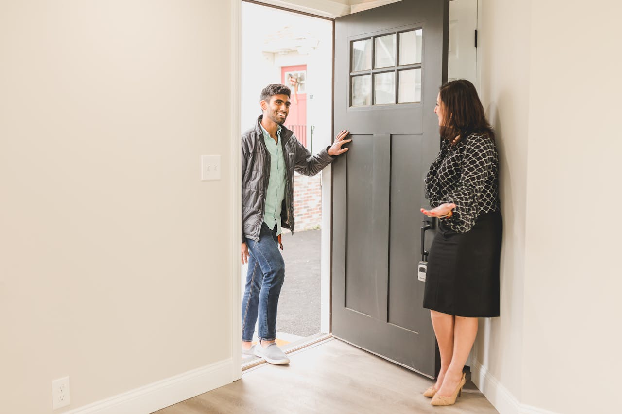 hero-img-02 Real estate agent greeting a client at the entrance of a new home, symbolizing a welcoming embrace for potential buyers.